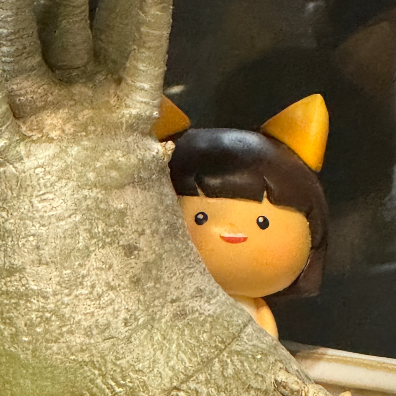 木の後ろから顔をのぞかせる「こんこんわらべ」のフィギュア。